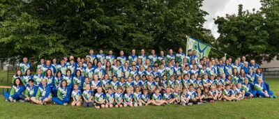 Gruppenfoto des STV Luechingen in Luechingen (9450, Kanton St Gallen) mit zahlreichen Mitgliedern in einheitlichen Vereinsfarben auf einer Wiese.