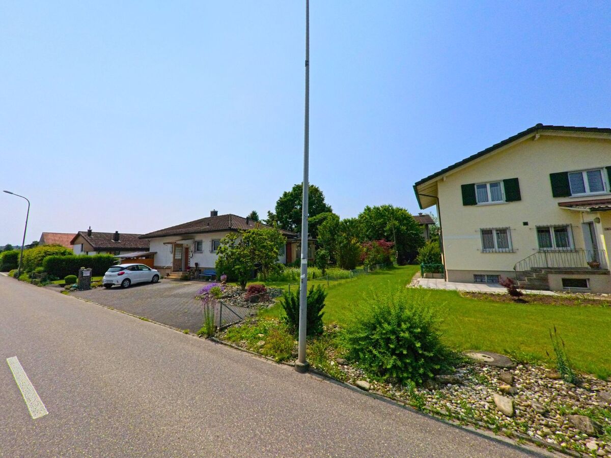 In Subingen (4553, Kanton Solothurn) führt eine ruhige Straße an mehreren Einfamilienhäusern mit gepflegten Gärten und Garageneinfahrten entlang.