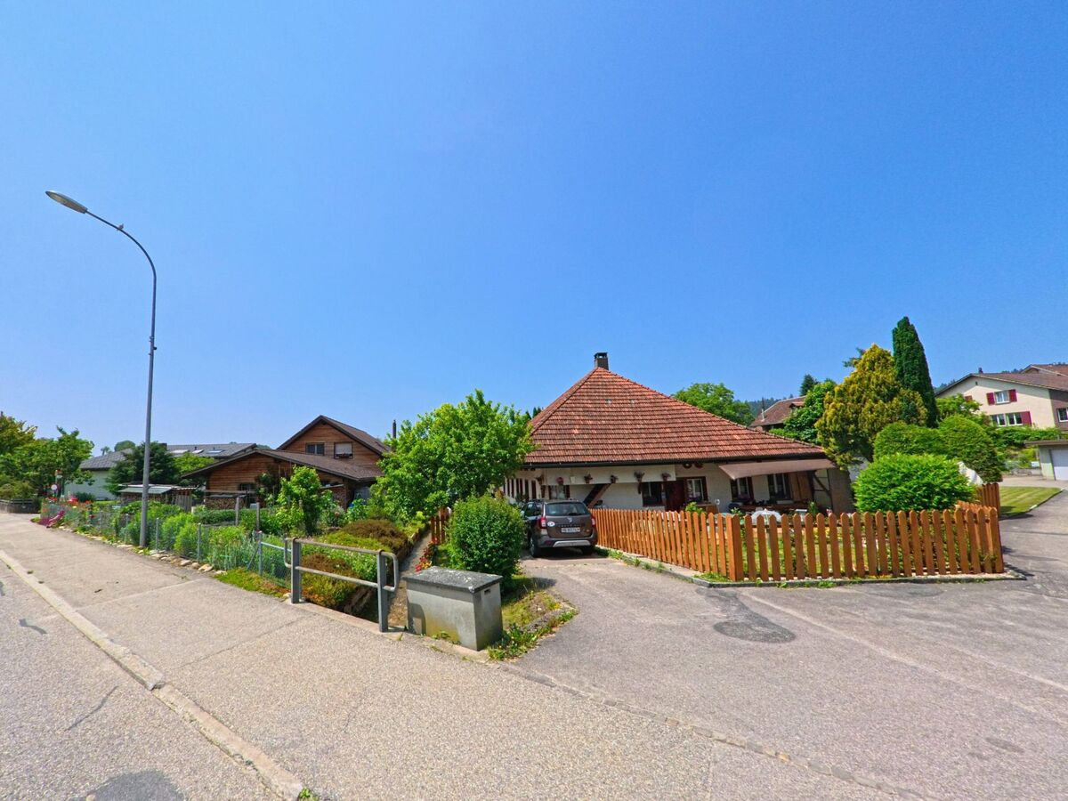 In Sumiswald (3455, Kanton Bern) ist ein traditionelles Einfamilienhaus mit einem gepflegten Garten und einem Holzzaun entlang einer ruhigen Strasse zu sehen.