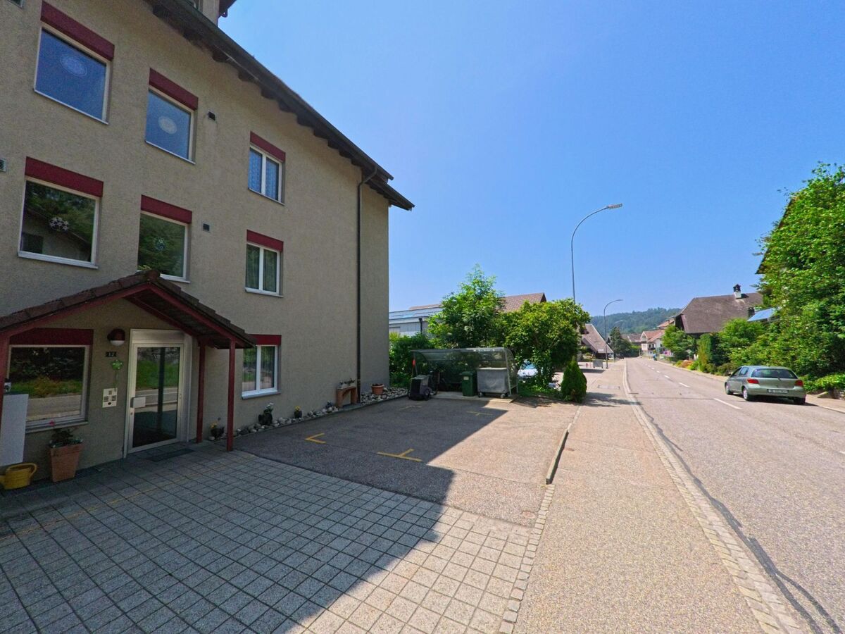 In Sumiswald (3455, Kanton Bern) ist ein mehrstöckiges Gebäude mit einem gepflegten Eingang und einer gut ausgebauten Strasse in Richtung der angrenzenden Häuser zu sehen.