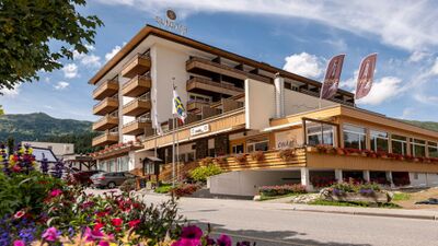 Das Sunstar Hotel in Lenzerheide (7078, Kanton Graubuenden) praesentiert sich mit Balkonen, Blumenschmuck und Bergkulisse im Hintergrund.