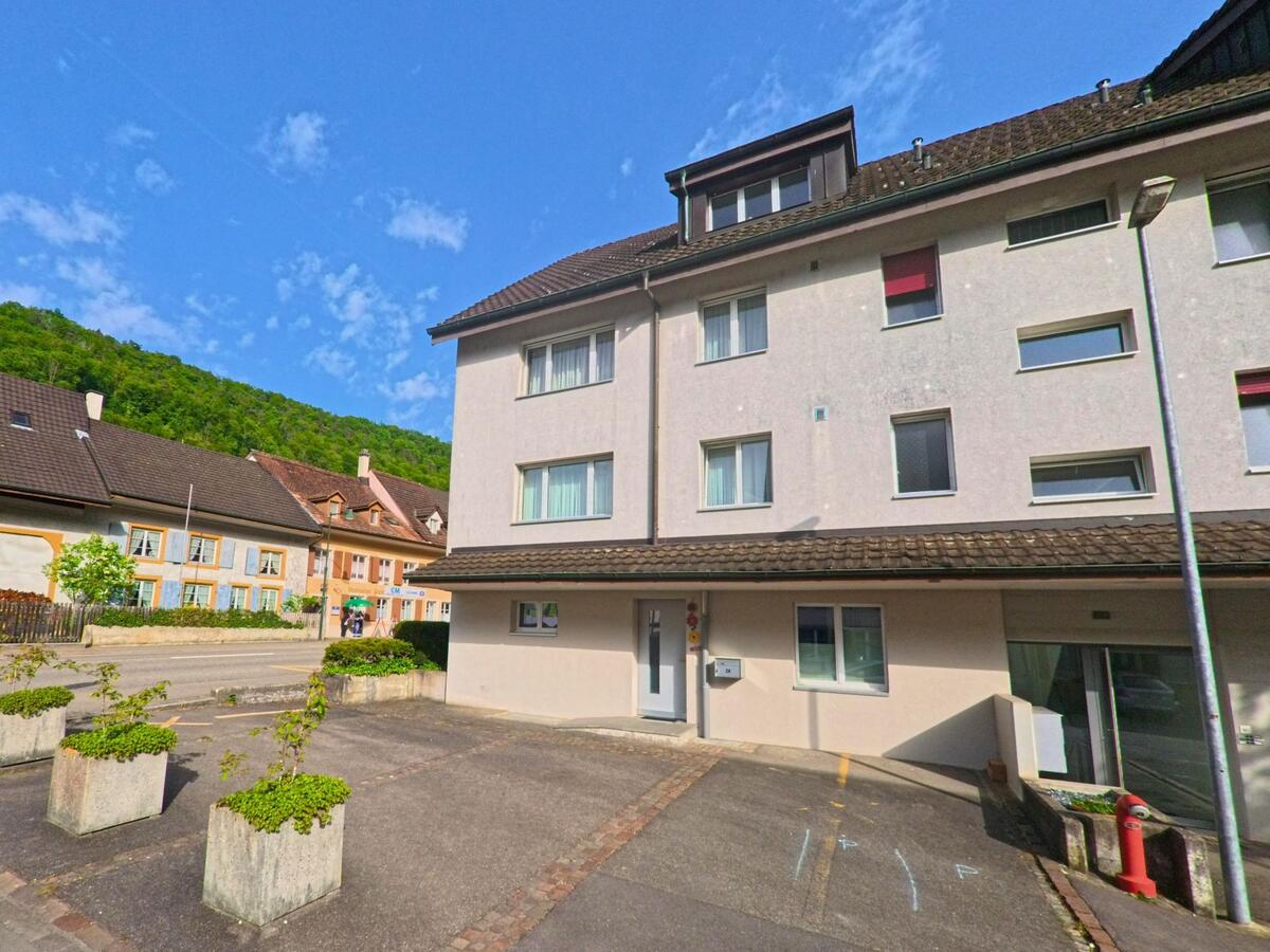 In Tecknau (4492, Kanton Basel-Landschaft) treffen moderne Mehrfamilienhäuser auf bunt gestrichene Altbauten entlang einer ruhigen Quartierstrasse.