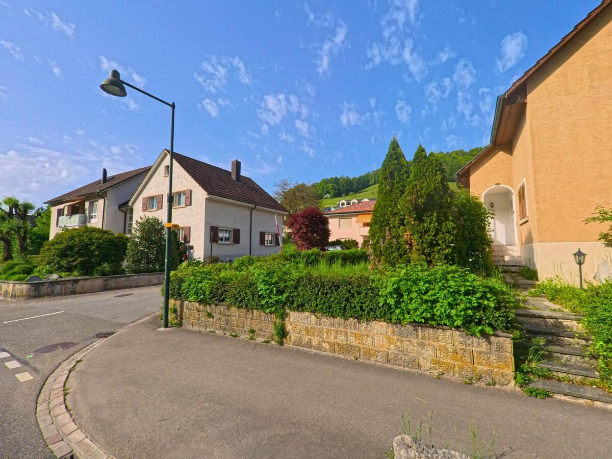In einem ruhigen Wohngebiet von Tecknau (4492, Kanton Basel-Landschaft) stehen gepflegte Einfamilienhäuser mit Vorgärten und bepflanzten Mauern.
