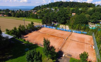 Mehrere Sandtennisplaetze liegen im Freien umgeben von Baeumen und Feldern in Kerzers (3210, Kanton Freiburg) und zeigen eine Sportanlage.