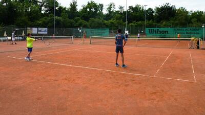 Kinder trainieren auf einem Sandtennisplatz mit Schlaegern und Baellen in Reinach (4153, Kanton Baselland) waehrend einer betreuten Uebungseinheit.