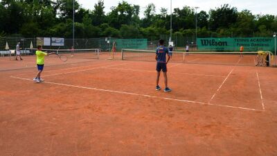 Kinder trainieren auf einem Sandtennisplatz mit Schlaegern und Baellen in Reinach (4153, Kanton Baselland) waehrend einer betreuten Uebungseinheit.