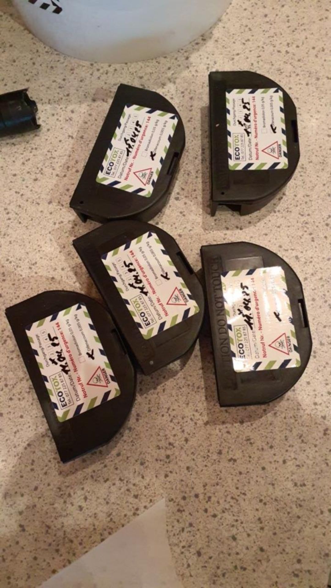 Auf einer Arbeitsfläche in Thalwil (8800, Kanton Zürich) liegen mehrere beschriftete schwarze Köderboxen der Marke Ecotox zur professionellen Schädlingsbekämpfung nebeneinander.