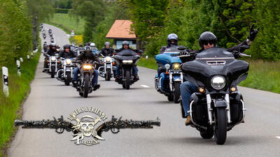 Auf einer Landstrasse in Hinwil (8340, Kanton Zürich) fährt eine Gruppe von Motorradfahrern gemeinsam durch eine grüne Landschaft, während mehrere Maschinen in Kolonne unterwegs sind.