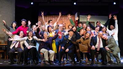 Die Mitglieder des Theater Einhorn Dübendorf in Dübendorf (8600, Kanton Zürich) posieren auf der Bühne für ein lebhaftes Gruppenfoto mit ausdrucksstarken Gesten.