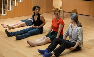 In einem hellen Probenraum im Theater Thalwil in Thalwil (8800, Kanton Zürich) sitzen mehrere Frauen auf dem Holzboden und sind in eine gemeinsame Bewegungs- und Theaterprobe eingebunden.