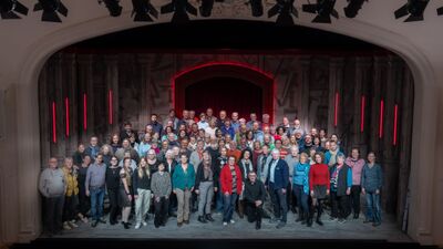 In Beinwil am See (5712, Kanton Aargau) versammelt sich die Theatergesellschaft auf der Bühne eines historischen Saals und zeigt sich in grosser Vielfalt der Mitwirkenden.