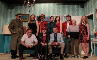 Die Theatergesellschaft Wettingen posiert in Wettingen (5430, Kanton Aargau) in unterschiedlichen Bühnenkostümen vor einer eingerichteten Theaterkulisse.