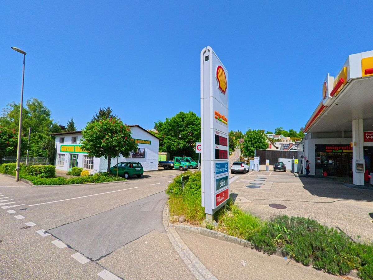 In Therwil (4106, Kanton Basel-Landschaft) liegt eine Tankstelle mit angrenzendem Shop und gegenüberliegendem Gebäude eines Gartenbetriebs an einer gut befahrenen Strasse.
