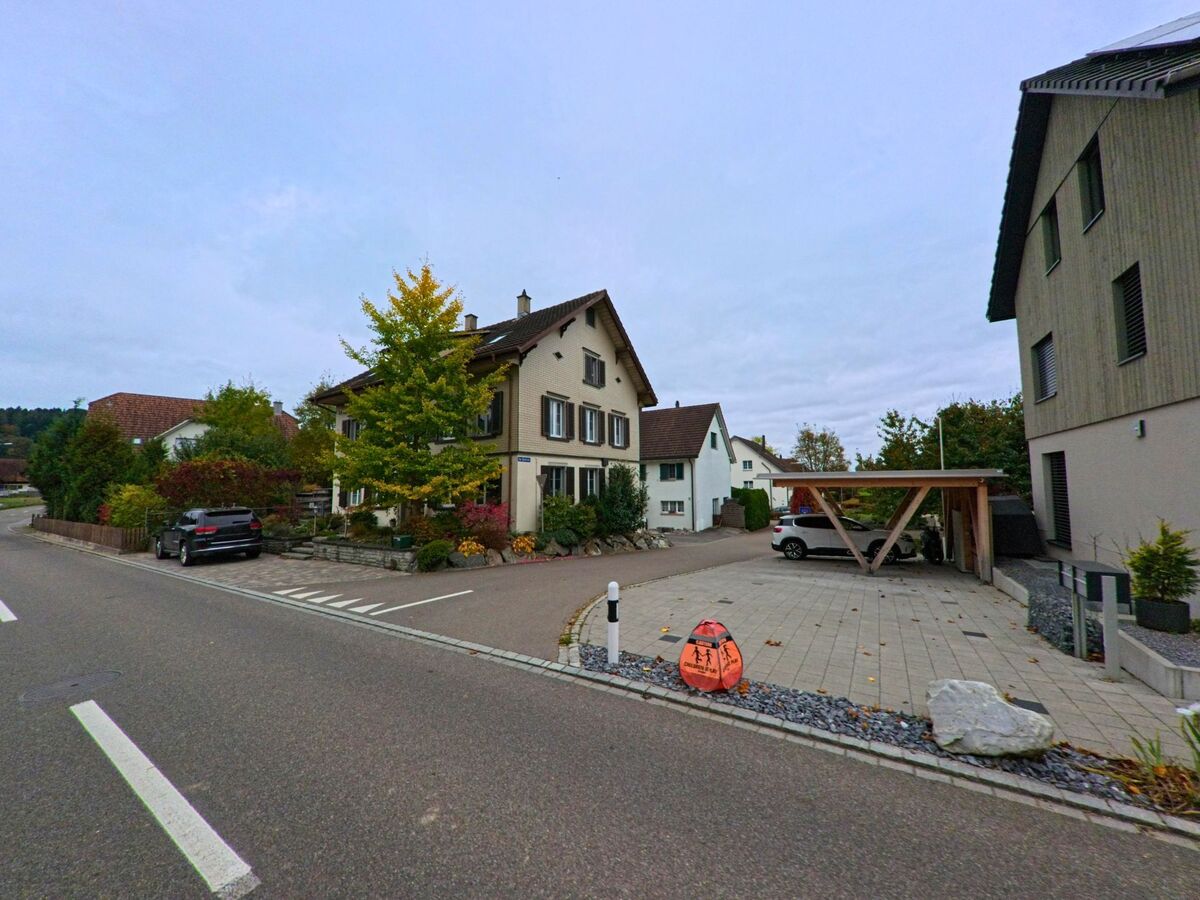 An einer ruhigen Quartierstrasse mit Einfamilienhaeusern und Carport zeigt sich in Thundorf (8512, Kanton Thurgau) ein gepflegtes Wohnumfeld mit bepflanzten Vorgartenbereichen.