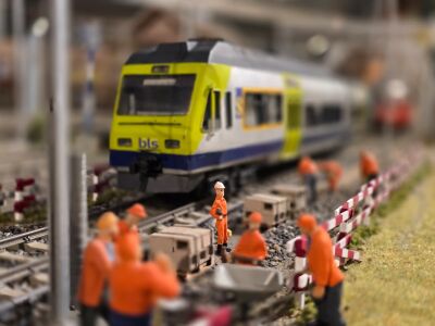 Auf einer Modellbahnanlage in Thun (3600, Kanton Bern) steht ein Zug auf den Gleisen, waehrend kleine Figuren Bauarbeiten entlang der Strecke darstellen.