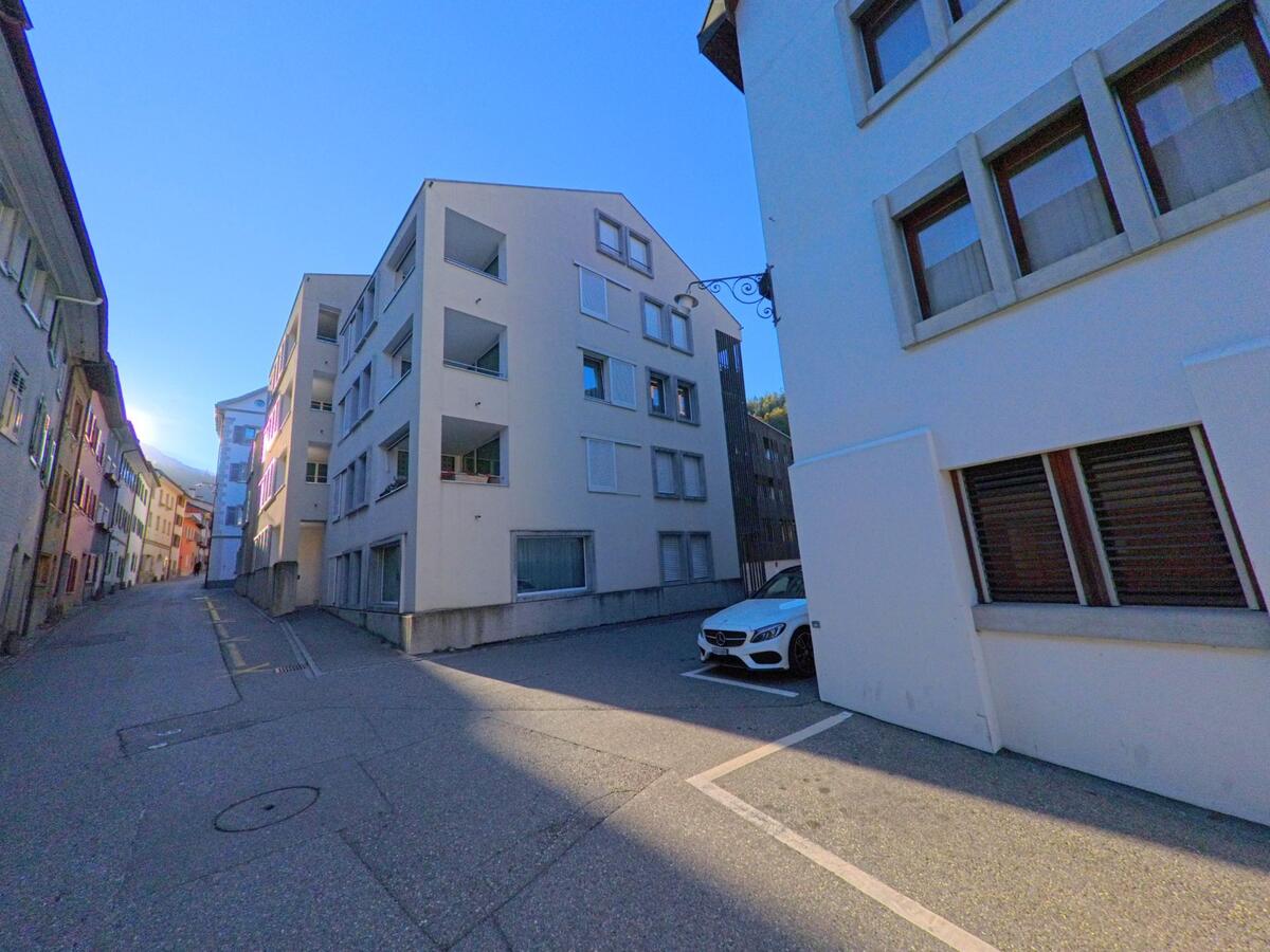 Zwischen modernen Mehrfamilienhäusern verläuft in Thusis (7430, Kanton Graubünden) eine schmale Seitenstrasse mit Parkplätzen und zurückhaltender Wohnbebauung.
