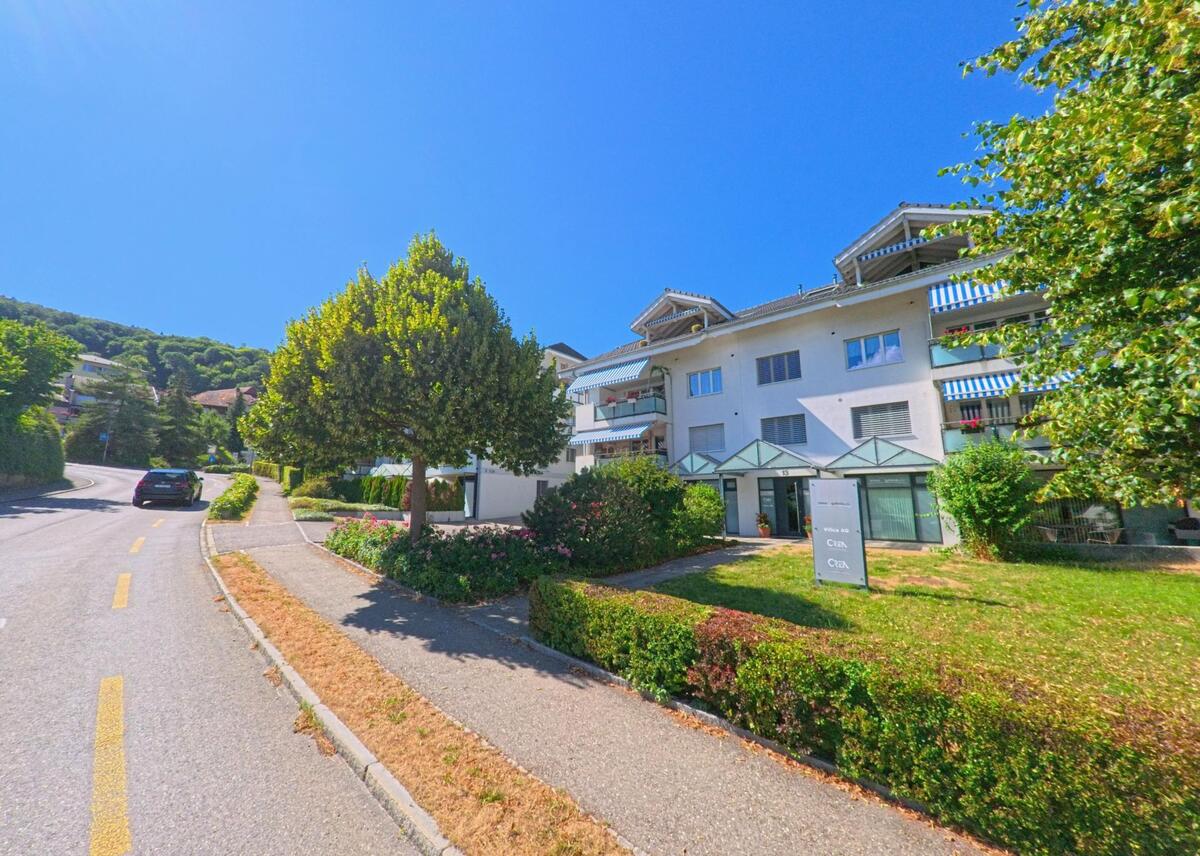 In Toffen (3125, Kanton Bern) steht ein modernes Mehrfamilienhaus mit Balkonen und gepflegter Grünanlage an einer sanft ansteigenden Wohnstrasse.