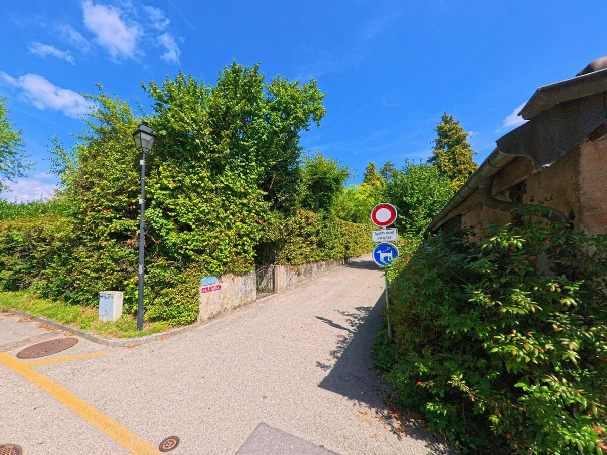 Ein schmaler Weg in Tolochenaz (1131, Kanton Waadt) fuehrt zwischen hohen Hecken hindurch, Verkehrsschilder weisen die Zufahrt nur fuer Anwohner aus.
