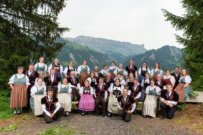 In Escholzmatt-Marbach (6196, Kanton Luzern) präsentiert sich eine grosse Gruppe in traditionellen Trachten vor einer bewaldeten Berglandschaft.