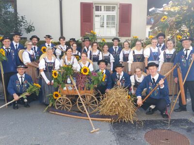 Vor einem Haus in Ruswil (6017, Kanton Luzern) praesentiert sich die Trachtengruppe Ruswil in festlicher Kleidung mit herbstlicher Dekoration und traditionellen Arbeitsgeraeten.