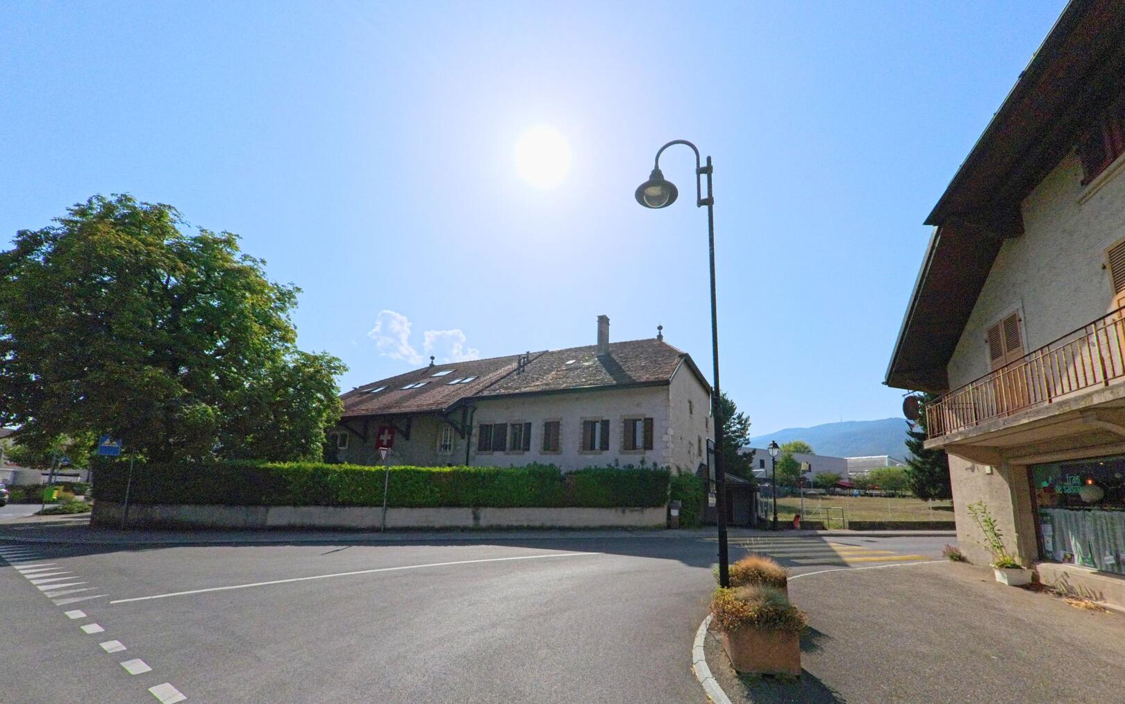 An einer Strasseneinmuendung in Trelex (1270, Kanton Waadt) stehen Wohnhaeuser mit traditionellen Daechern, waehrend ein Kammerjaeger im Einsatz ist.