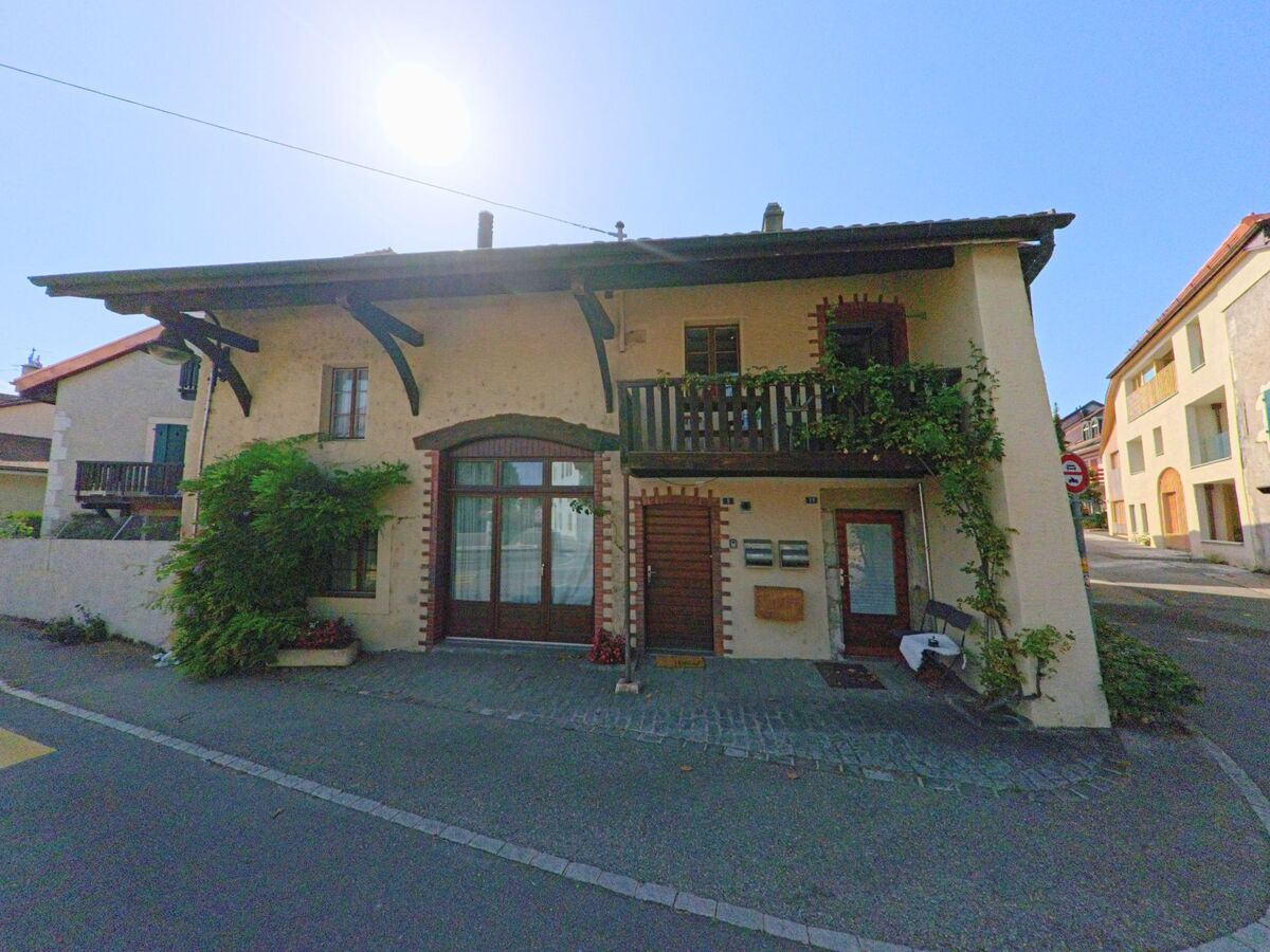 Ein traditionelles Wohnhaus mit Holzbalkon und Begruenung steht in Trelex (1270, Kanton Waadt), wo ein Kammerjaeger eine Kontrolle durchfuehrt.