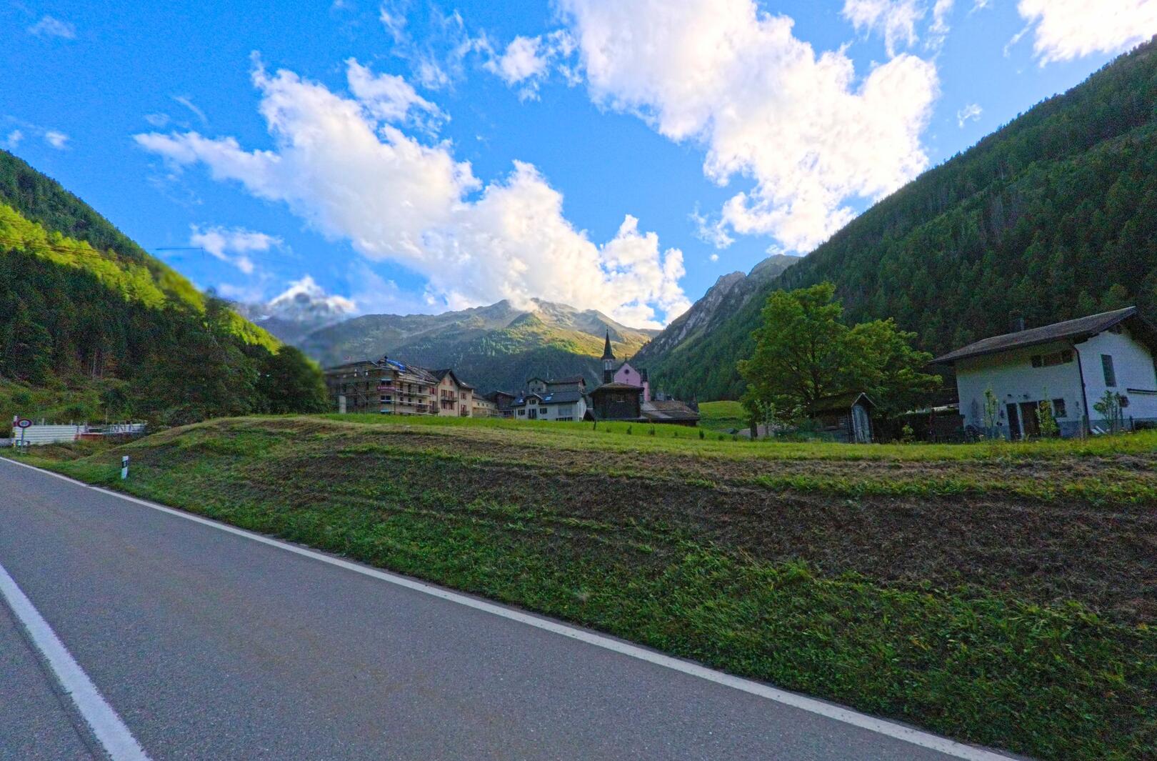 Am Ortsrand von Trient (1929, Kanton Wallis) liegen Wohnhaeuser und die Kirche inmitten eines von Bergen umgebenen Tals.
