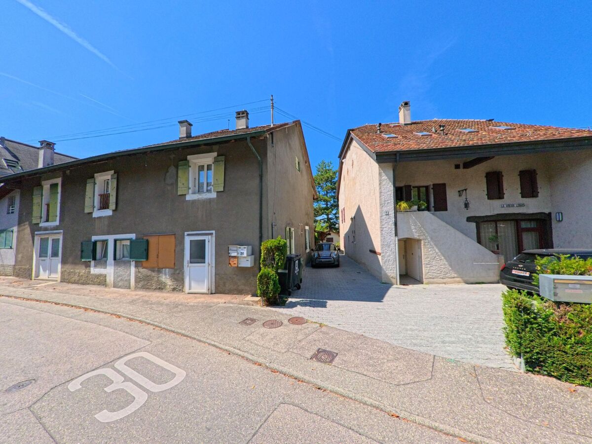 In Troinex (1256, Kanton Genf) stehen traditionelle Wohnhaeuser mit Fensterlaeden und schmaler Hofeinfahrt nebeneinander.