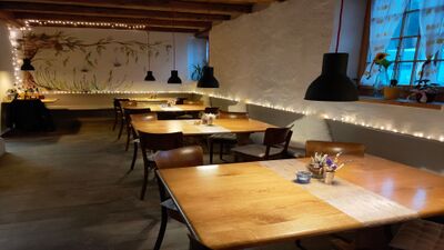 In der Trotte Ruedlingen (8455, Kanton Schaffhausen) schaffen Holzmoebel, sanftes Licht und eine bemalte Wand mit Lichterkette eine gemuetliche Atmosphaere im Gastraum.