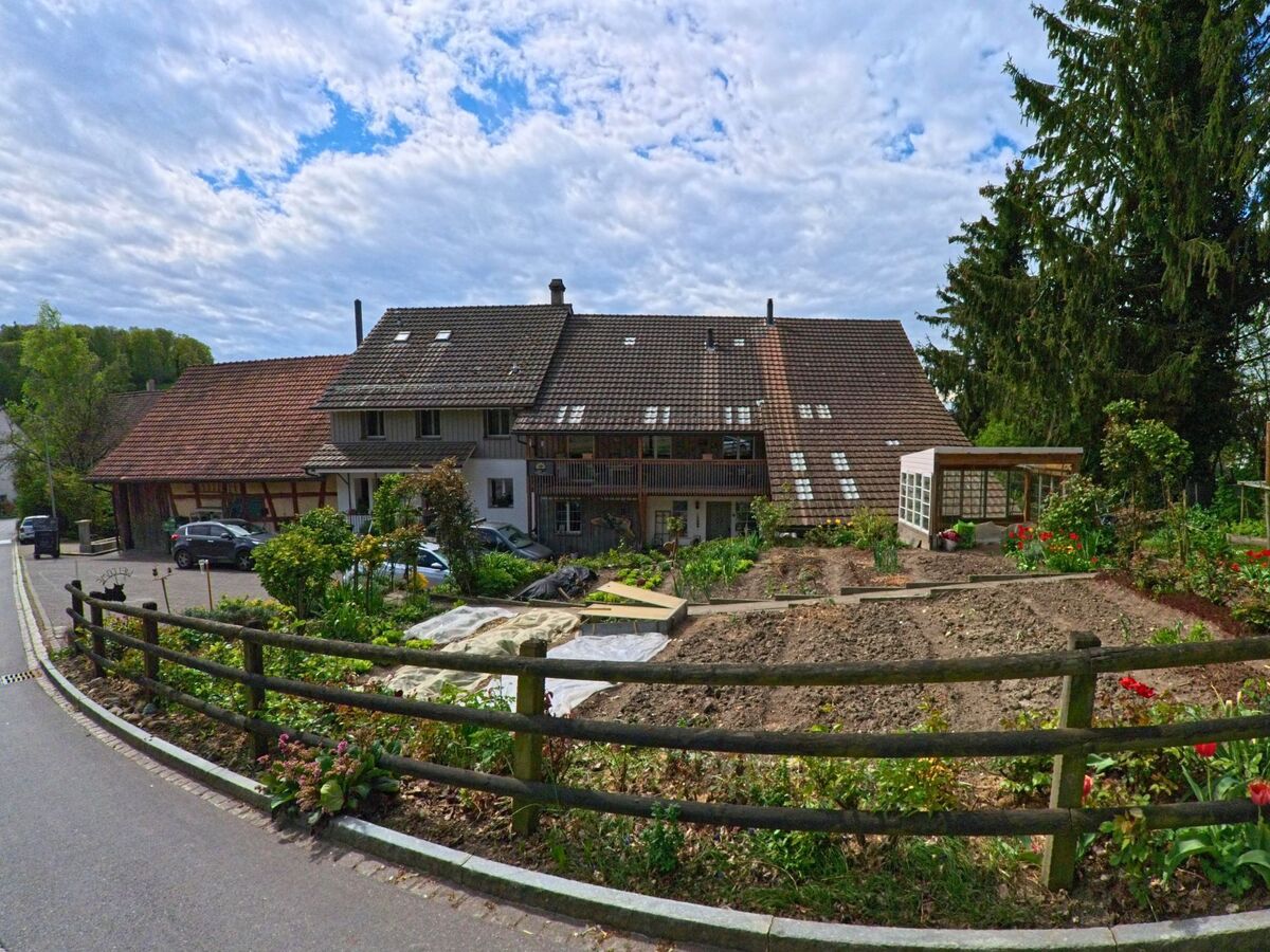 Ein Wohnhaus mit grossem Gemuese- und Blumengarten liegt in Truellikon (8466, Kanton Zuerich) direkt an einer schmalen Strasse.