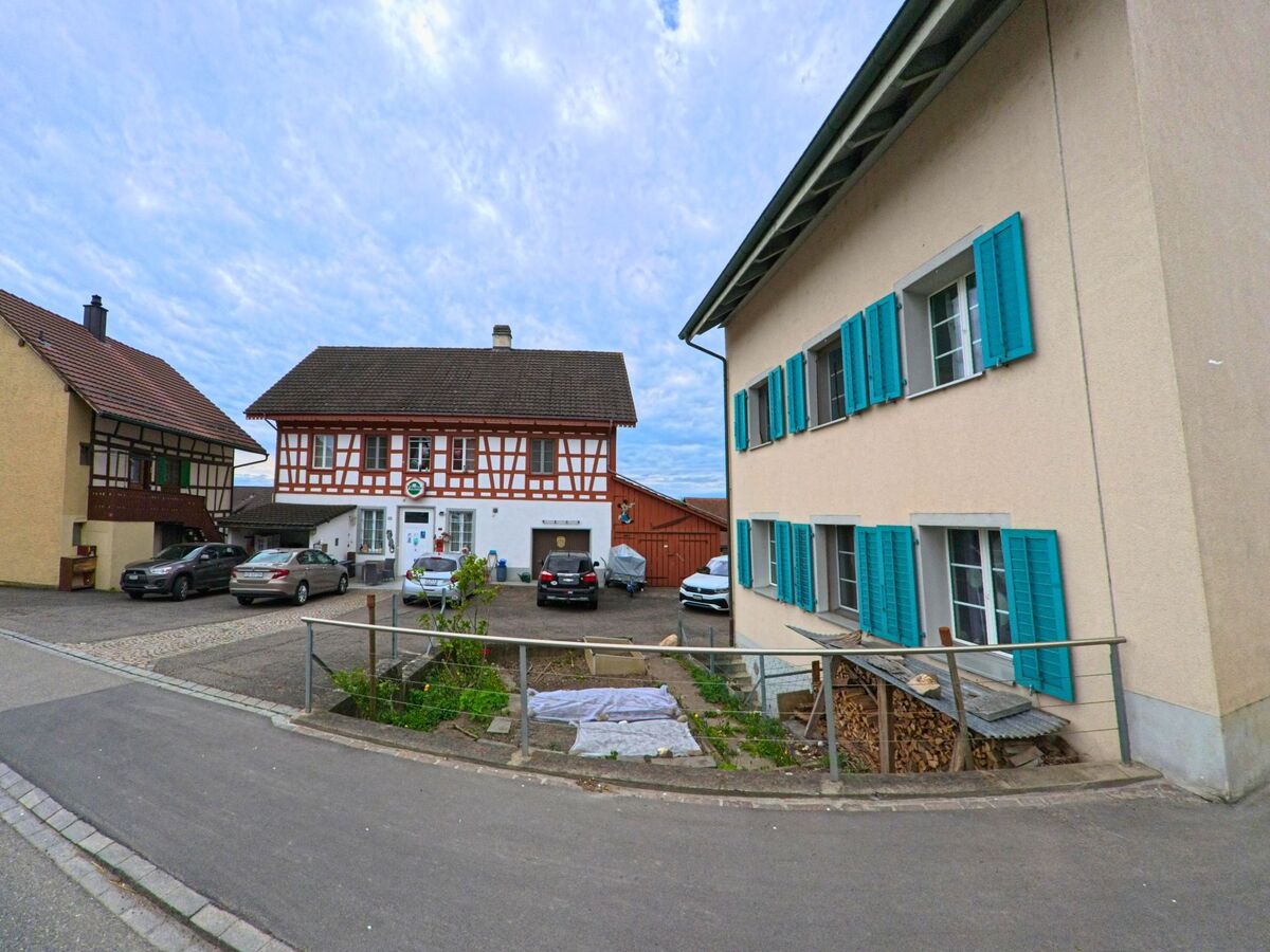 In einer Seitenstrasse von Truttikon (8467, Kanton Zürich) stehen traditionelle Wohnhäuser, darunter ein auffälliges Fachwerkhaus mit einem Schild über dem Eingang.
