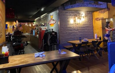 In Wil (9500, Kanton St. Gallen) zeigt das T's Barbecue Restaurant einen amerikanisch inspirierten Innenraum mit Dekoration, Neonlichtern und rustikalen Holztischen.