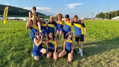 Auf einer Wiese feiern Mitglieder des Turnvereins in Nussbaumen (8537, Kanton Thurgau) gemeinsam in Sportkleidung nach einem Wettkampf bei sonnigem Wetter.