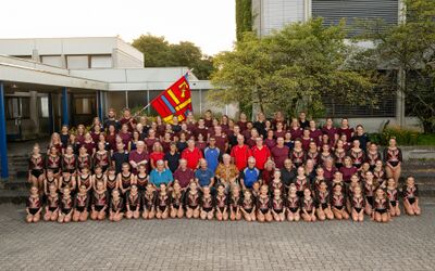 Vor einem Gebaeude in Thun (3600, Kanton Bern) steht eine grosse Gruppe von Kindern, Jugendlichen und Erwachsenen in Reihen fuer ein gemeinsames Gruppenfoto.