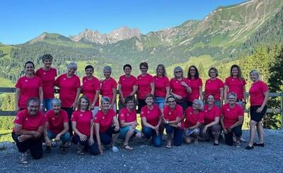 Vor einer Berglandschaft in Gommiswald (8725, Kanton St. Gallen) posiert eine Turngruppe in einheitlichen roten Shirts für ein gemeinsames Gruppenbild.