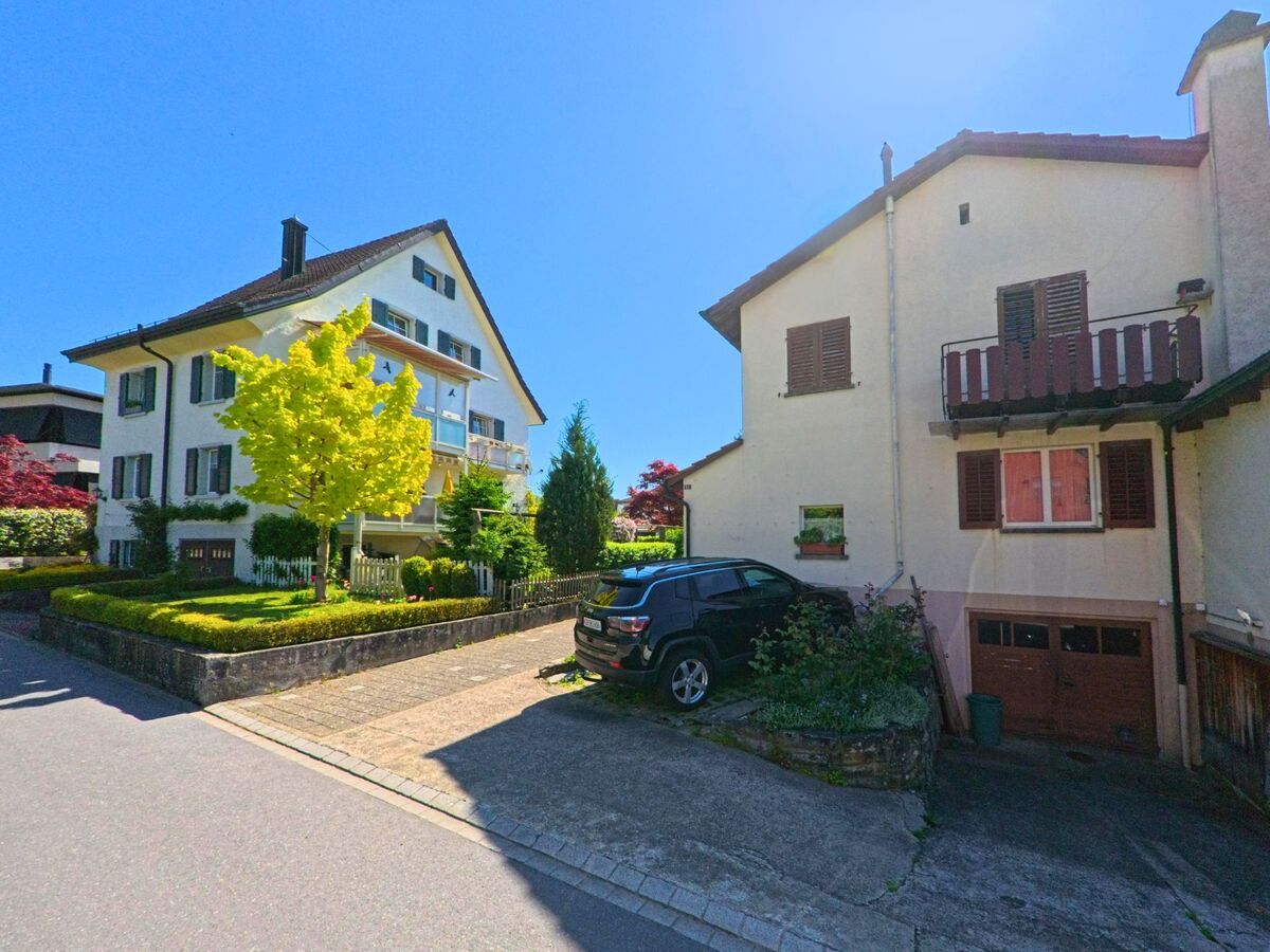 Zwischen gepflegten Vorgärten und Garagen stehen in Uetikon am See (8707, Kanton Zürich) zwei Einfamilienhäuser an einer ruhigen Quartierstrasse.