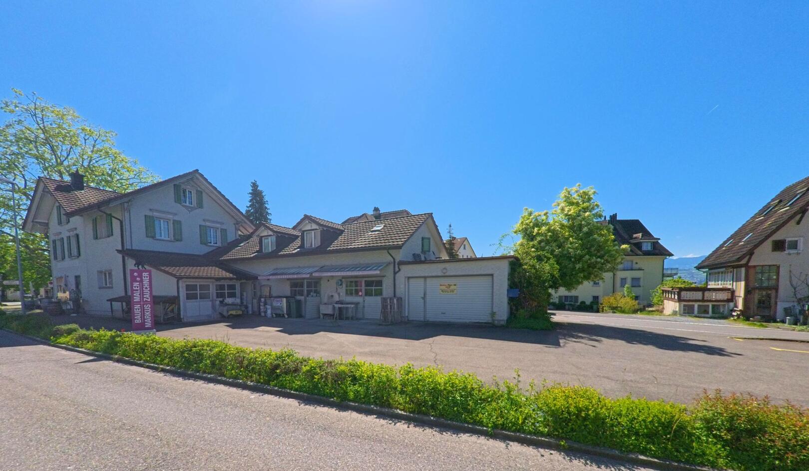 In Uetikon am See (8707, Kanton Zürich) liegt bei strahlend blauem Himmel ein kleiner Gewerbebetrieb mit Werkstatt und Wohnhaus an einer ruhigen Seitenstrasse.