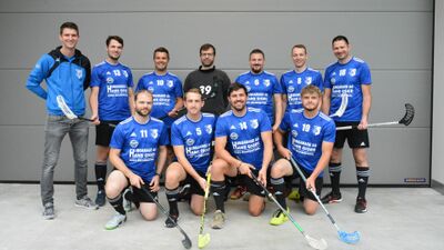 In Richenthal (6263, Kanton Luzern) posiert die Mannschaft des UHC Cannibals Richenthal in blauen Trikots mit weissen Logos für ein Gruppenfoto, während einige Spieler mit ihren Schlägern in der Hand knien oder stehen.