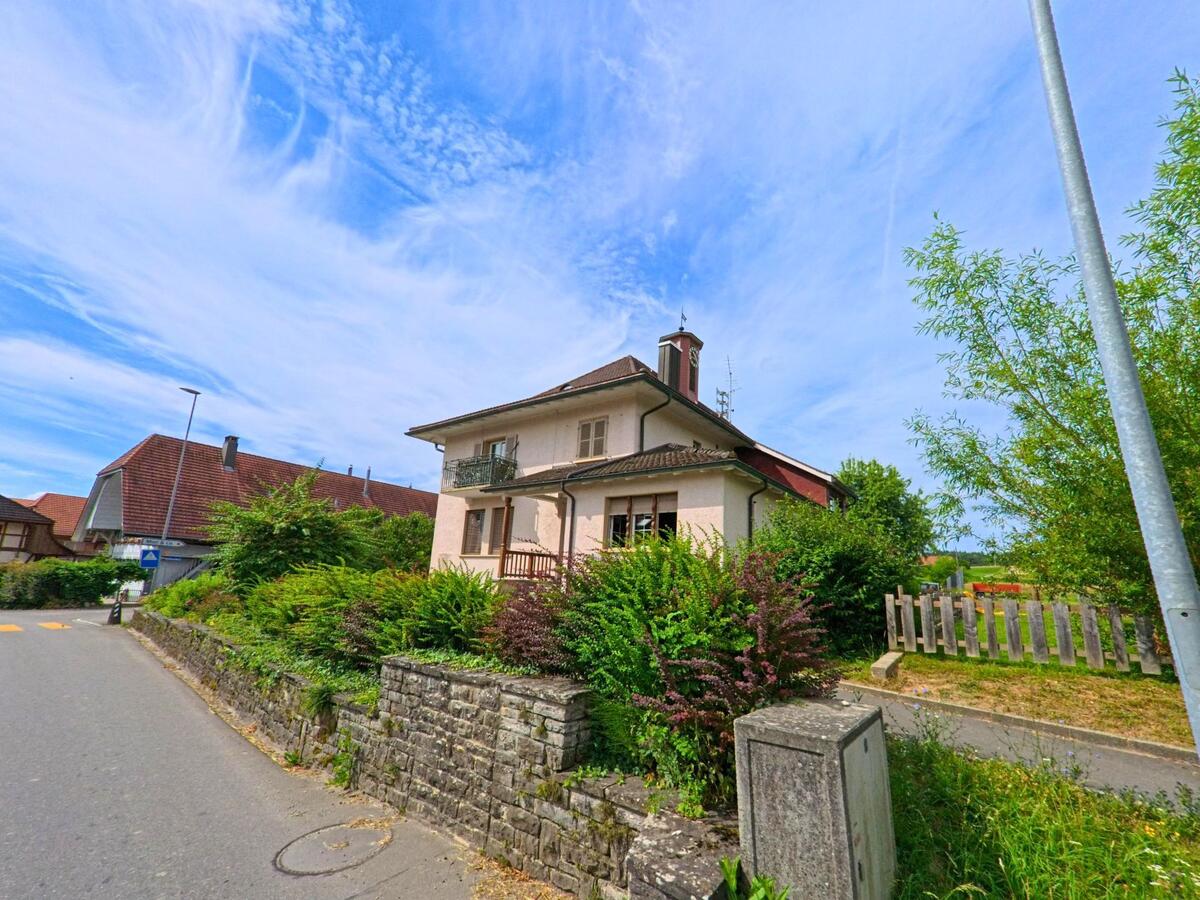 In Ulmiz (3214, Kanton Freiburg) steht ein zweistöckiges Wohnhaus mit gepflegtem Garten an einer leicht ansteigenden Quartierstrasse.