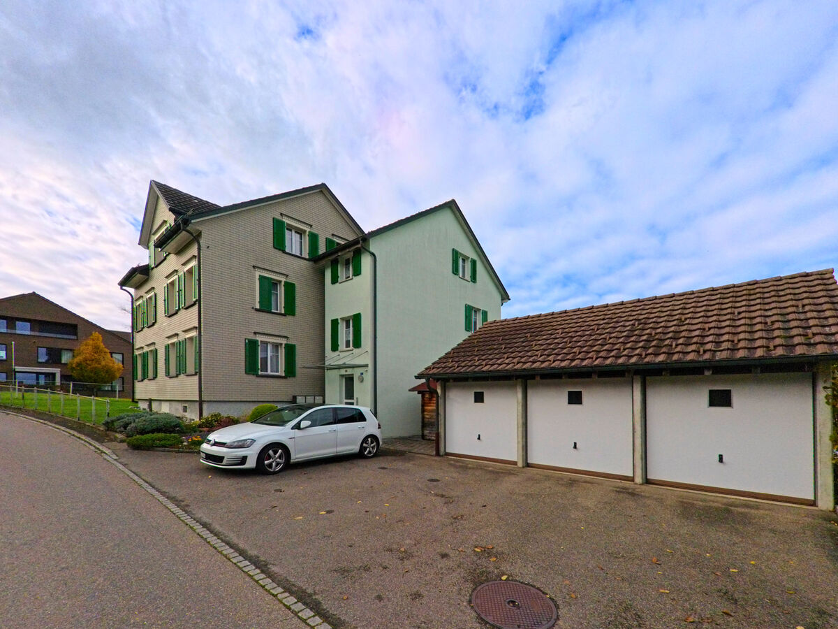 Ein Mehrfamilienhaus mit Garagen steht an einer ruhigen Quartierstrasse in Untereggen (9303, Kanton St. Gallen).