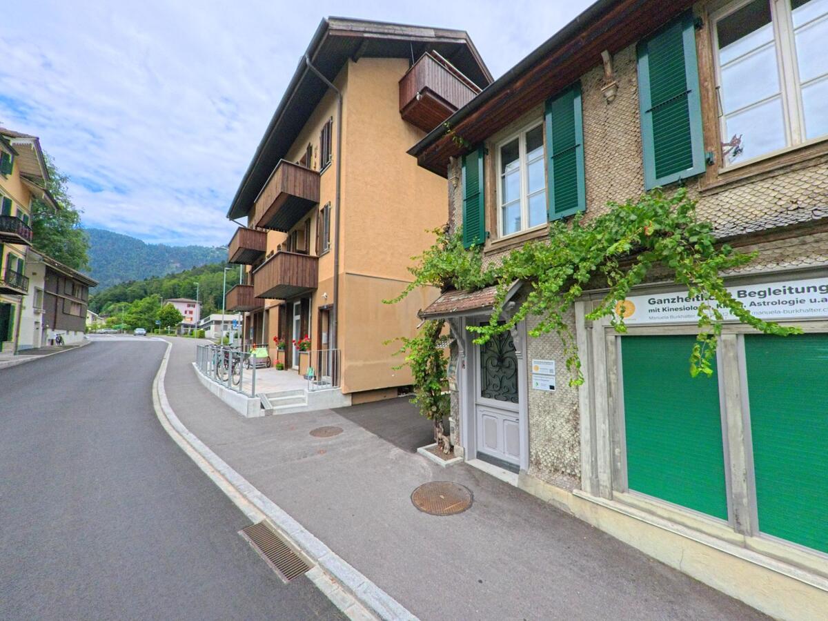 In Unterseen (3800, Kanton Bern) säumen sanierte Wohnhäuser mit grünen Fensterläden und Balkonen eine ruhige, ansteigende Strasse am Hang.