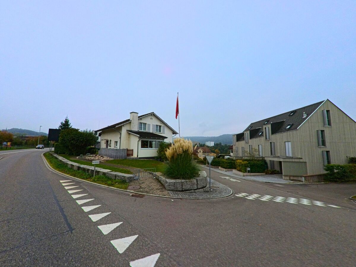 An einer übersichtlichen Kreuzung mit Wohnhäusern und gepflegten Grünflächen zeigt sich ein Quartier von Untersiggenthal (5417, Kanton Aargau) unter freiem Himmel.