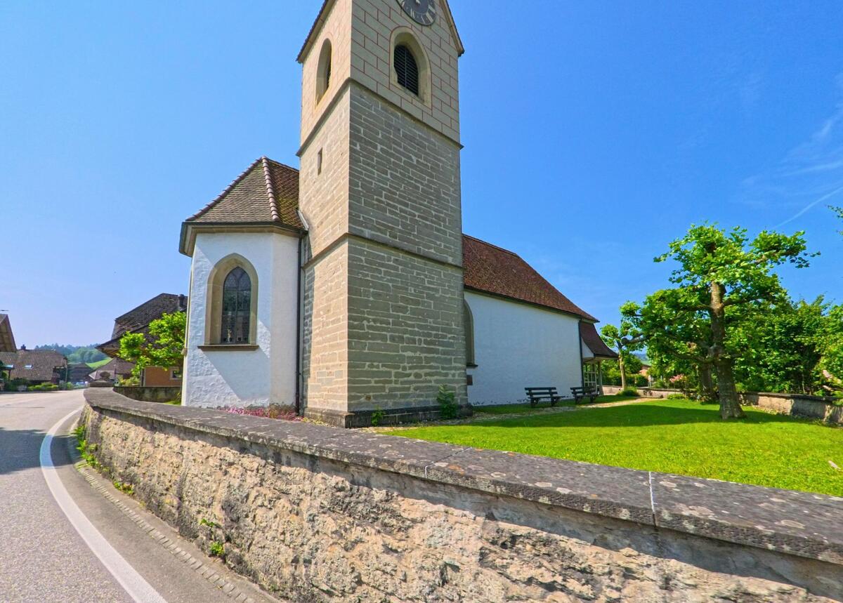 Die reformierte Kirche von Ursenbach (4937, Kanton Bern) mit ihrem markanten Turm und gepflegtem Kirchhof liegt an einer sanft geschwungenen Strasse im Dorfzentrum.
