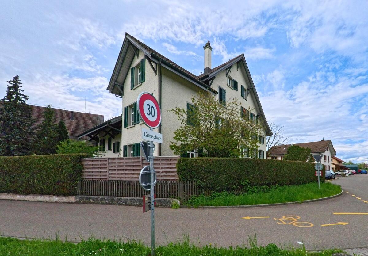 In einem Wohnquartier von Uster (8616, Kanton Zürich) beginnt eine verkehrsberuhigte Zone mit Tempo-30-Schild und eingezeichnetem Veloweg.