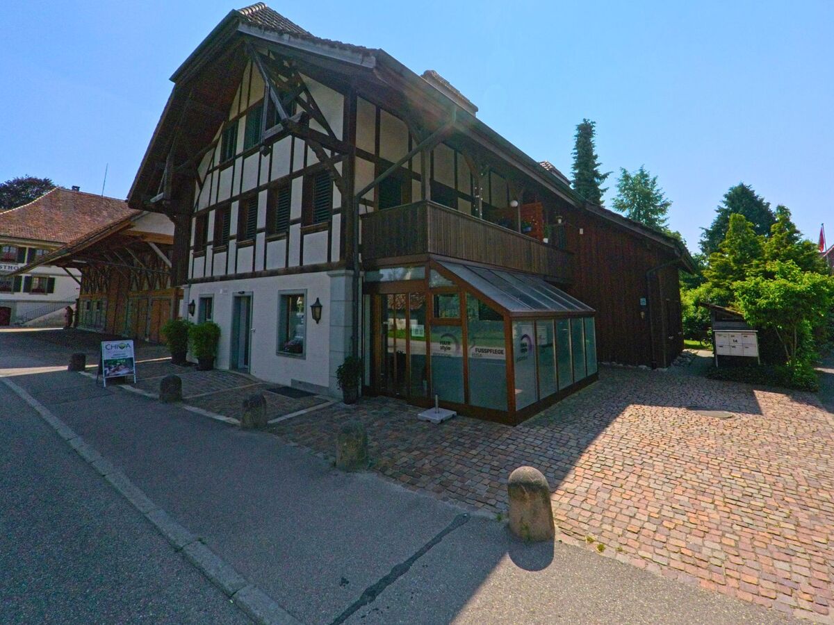 Ein traditionelles Fachwerkhaus mit Praxisräumen steht in Utzenstorf (3427, Kanton Bern) an einer gepflasterten Nebenstrasse im historischen Dorfkern.