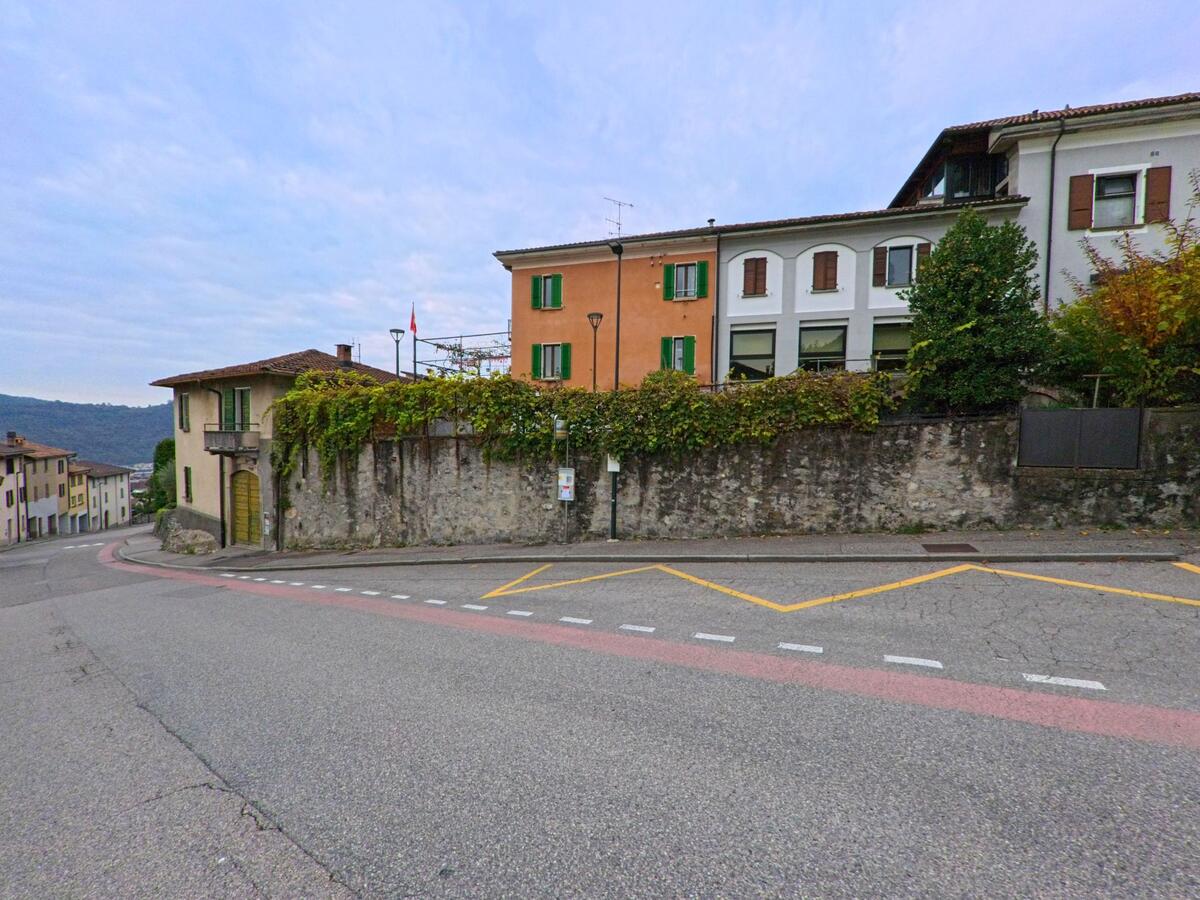 An einer leicht abfallenden Strasse in Vacallo (6833, Kanton Tessin) stehen traditionelle Häuser mit farbigen Fassaden und grünen Fensterläden.