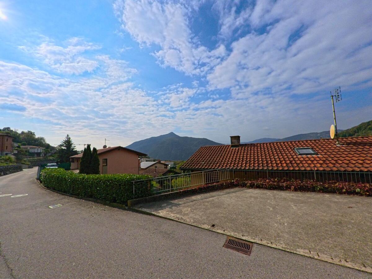 Ein Wohnquartier mit Haeusern und roten Ziegeldächern in Val Mara (6818, Kanton Tessin) bietet einen weiten Blick auf die umliegenden Berge.