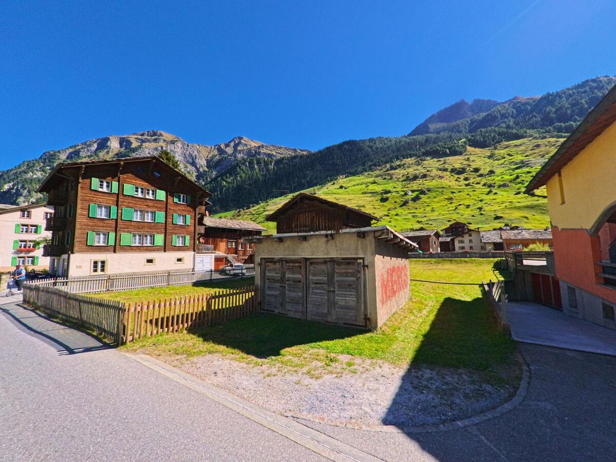 Traditionelle Holzhäuser mit grünen Fensterläden prägen in Vals (7132, Kanton Graubünden) das Dorfbild am Fuss der sonnigen Berghänge.