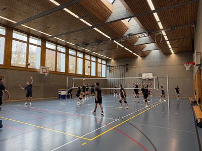 In einer Sporthalle in Gommiswald (8737, Kanton St. Gallen) trainieren die Mitglieder des VBC Gommiswald gemeinsam am Volleyballnetz.