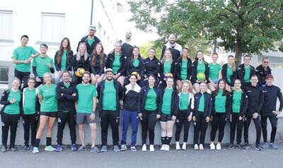 Die Mitglieder des VBC Linth aus Kaltbrunn (8722, Kanton St. Gallen) posieren gemeinsam in grüner und schwarzer Vereinskleidung, einige halten Volleybälle.